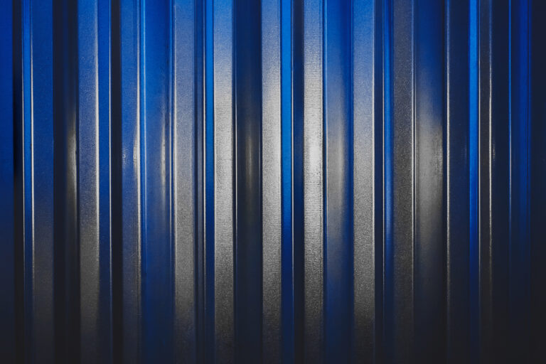 Galvanized iron fence with bright white spot in blue texture background.